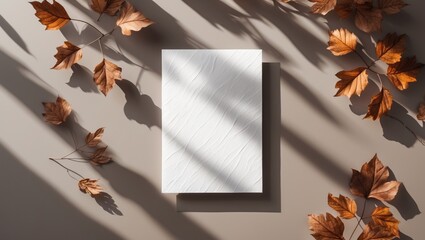 Poster - Blank textured paper on a neutral background surrounded by autumn leaves casting shadows in natural light