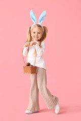 Wall Mural - Cute little girl in bunny ears with basket of chocolate Easter eggs on pink background