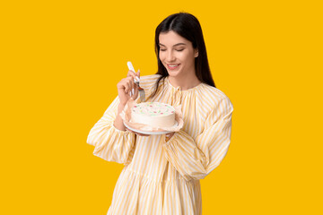 Wall Mural - Beautiful young woman with sweet bento cake and fork on yellow background. International Women's Day