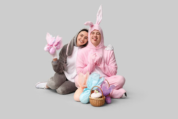 Wall Mural - Beautiful young couple in bunny costume with Easter basket and gift eggs on grey background