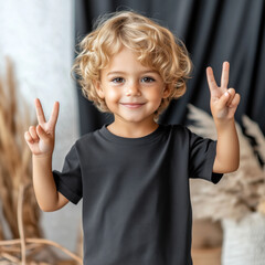 Wall Mural - Kids basic black t-shirt mockup. Curly hair boy model, peace sign hands, in short sleeve crewneck tee, front view. Children's blank casual shirt template. Birthday, summer holiday, vacation designs 
