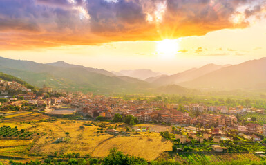 Wall Mural - scenic panorama of italian town during sunset with amazing view from above to nice city with picturesque mountain valley landscape and cloudy sky on backdrop