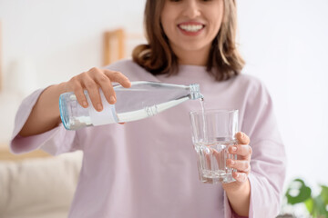 Wall Mural - Young woman drinking water  at home