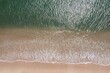 © Wirestock - Aerial view of a serene beach with gentle waves.