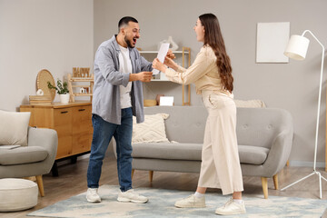 Wall Mural - Happy young woman showing refund form to her husband at home