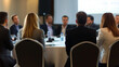 © zhou yan - Business professionals sitting at a round table during a conference or presentation in a hotel, captured from behind with sharp focus and professional color grading. This high-quality image, showcasin
