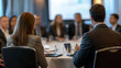 © zhou yan - Business professionals sitting at a round table during a conference or presentation in a hotel, captured from behind with sharp focus and professional color grading. This high-quality image, showcasin