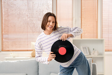 Wall Mural - Young woman with vinyl disk dancing at home