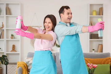 Wall Mural - Young couple with spray bottles cleaning in room on spring day