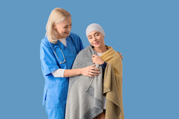 Wall Mural - Young woman after chemotherapy with plaid and nurse on blue background. Brain cancer concept