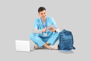 Poster - Male medical intern writing in notebook on grey background