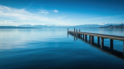 Aufkleber - Tranquil lakeside view with a wooden dock reflecting mountains in the distance during midday under clear blue skies. Generative AI