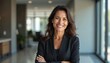 © miss irine - Pro mid aged Latin business woman corporate leader smiles. Positive mature female executive manager stands in office arms crossed, looks at camera. Confident lady, success in business. Leadership.