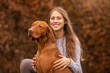 © Annabell Gsödl - A young teenager girl and her magyar vizsla dog cuddle together outdoors, autumn colors