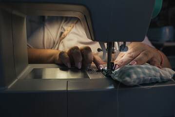 seamstress sewing fabric with sewing machine at night