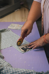 seamstress cutting fabric with rotary cutter on purple cutting mat
