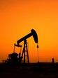 © Світлана Старецька - Oil pump jack stands prominently against a stunning orange sunset. The machinery's silhouette highlights the rural setting, emphasizing energy production at dusk.