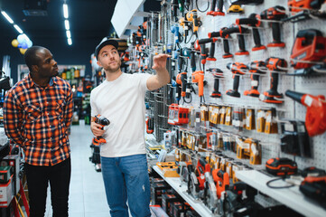 Sticker - Buying a drill or screwdriver. A consultant in a hardware store advises a male customer on the purchase of a new screwdriver