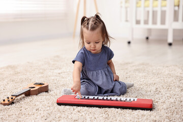 Wall Mural - Cute little girl playing with toy piano at home