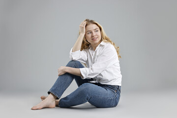 Wall Mural - Smiling woman in stylish jeans on grey background