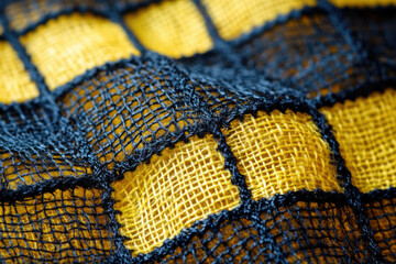 Poster - Close-up of yellow fabric with black net overlay, creating a textured, patterned design.