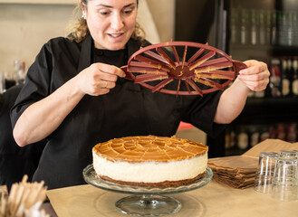 woman pastry chef small business owner marks the pieces of a vegan cheesecake for cutting