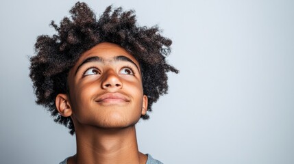 Wall Mural - A young male, possibly a teen or young adult, stands confidently against a light background with a look of contentment on his face, showcasing a casual, urban style.