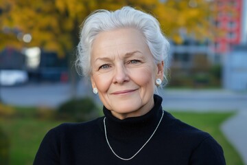 Wall Mural - A woman with gray hair and a black sweater is smiling. She is wearing a necklace and earrings