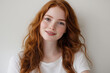 © amavcoffee - Portrait of a young woman with long, wavy red hair on a light grey background