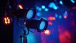 © Tom - Two vibrant stage lights cast a blue glow in a colorful setting, enhancing the atmosphere of a live performance.
