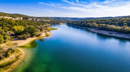 Poster - Aerial view of a serene river winding through vibrant green forests and hills under a bright blue sky : Generative AI