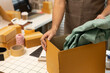 © Somdetmeaow - A man is working on a table with several boxes and a roll of tape. The boxes are stacked on top of each other, and the tape is being used to seal them