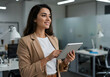 © PRINTZTASTIC - Elegant Businesswoman Analyzing Data on Her Tablet in a Modern Office.