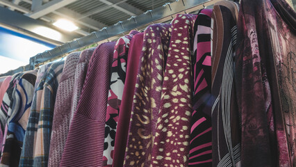 Poster - A rack of clothes with a red shirt on the left and a brown shirt on the right. The clothes are hanging on a rack and are of different colors and styles