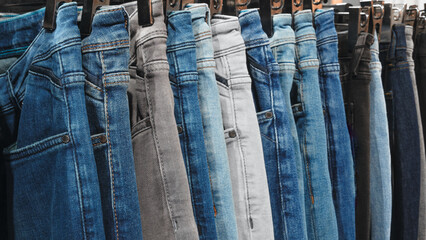Poster - A row of jeans hanging on a rack. The jeans are of different colors and styles. Concept of variety and choice, as the person hanging the jeans can pick from a wide range of options