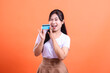 © Ajab - Happy young woman holding a blue credit card and winking, smiling and cheerful expressing joy and shopping, isolated on orange background