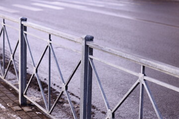 Poster - A metal fence running alongside a road, perfect for use in images about infrastructure, transportation, or urban landscapes.