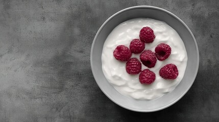 Wall Mural -  A bowl brimming with yogurt and raspberries graces a gray counter, framed by black and white