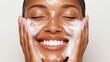 © Chanagun - A joyful woman enjoying her skincare routine, applying face cleanser with a big smile. Her glowing skin reflects self-care and confidence, embodying wellness and beauty.