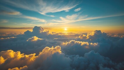 Wall Mural - Aerial perspective captures a stunning yellow sunrise above dense, white clouds against a blue sky.