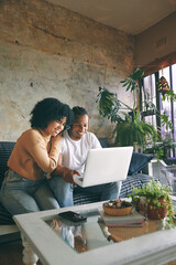 Poster - Laptop, love and couple on sofa in home for reservation of romantic weekend trip with online hotel checkin. Happy, relax with African man and woman, computer and booking honeymoon vacation in house.