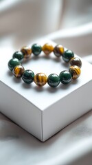 Poster - Close-up view of exquisite gemstone bracelet with green and brown colors arranged in a repeating pattern on soft fabric : Generative AI