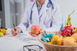 © R Photography - A male nutritionist works at his desk, discussing the benefits of eating fruit. He analyzes diets and educates patients on healthy eating habits for optimal health and well-being
