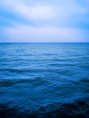 Poster - Serene view of calm blue ocean water with subtle waves under a cloudy sky in the evening : Generative AI