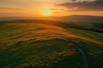 Poster - Sunset glow casts a warm light over rolling grassy hills in a tranquil landscape, Sunset glow on beautiful grassy hills - majestic drone shot