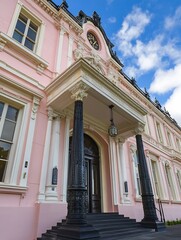 Poster - Elegant Pink Historic Building with Intricate Architecture Against a Bright Blue Sky : Generative AI