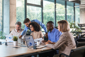 Wall Mural - Successful businesspeople working in a coworking space working with laptop discussing strategy and business plan in modern office.