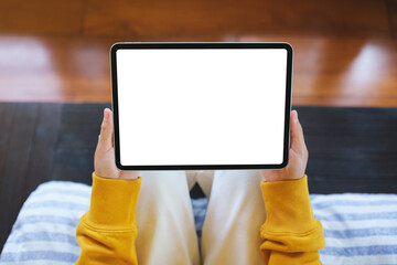 Wall Mural - Top view mockup image of a woman holding tablet with blank desktop white screen while sitting on the bed at home