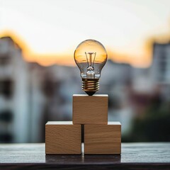 Poster - Illuminating Ideas:  Lightbulb on Wooden Blocks at Sunset, Symbolizing Innovation and Growth.  Achieving Goals Through Creative Solutions.