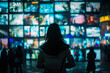 © Duka Mer - A woman in front of multiple screens displaying various video content, representing online media and streaming culture with a dark, contrasting background.